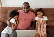 Streaming Service Parental Controls: How & Why To Set Them Up A father and his two daughters sitting on a couch while streaming on a laptop