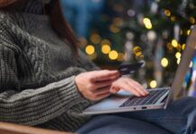 How to Spot Holiday Fraud and Shop Safely This Season Female hands on the laptop with credit card and blurred bokeh lights