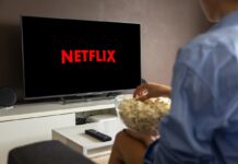 The Rise of Account Sharing: Is It a Gateway to Piracy? A person enjoying popcorn while watching Netflix.