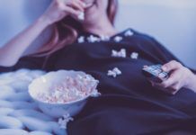 Avoiding Illegal Streaming on 123Movies Woman on a couch eating popcorn