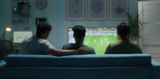 Illegal Sports Streaming Sites to Avoid in 2026 Three young men sitting on the sofa while streaming a soccer match on TV at home.