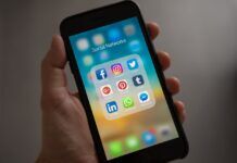 The Role of Social Media in Spreading Pirated Content: Risks and Responsibilities person holding an iphone showing a social media folder