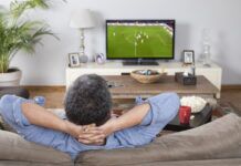 Where to Watch the Champions League Final 2023 Man relaxing on the couch while watching the Champions League Final soccer match on TV