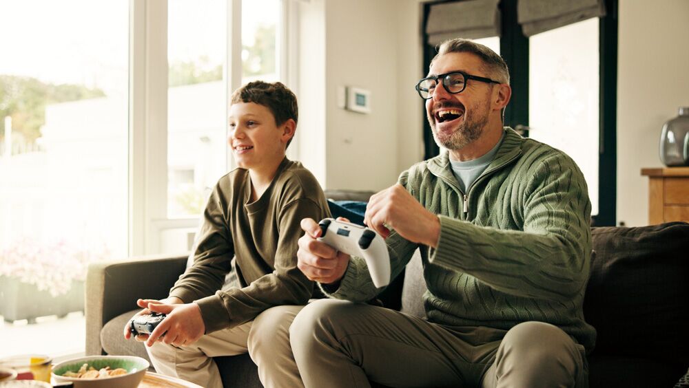 Summer_Gaming2 Father, child and play video game with celebration, win competition and parent with son in home. Happy kid, dad and success with console with fist pump, happiness and bonding together with family