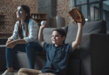 How To Watch Every Game of the 2024 MLB Postseason Young boy with a baseball and glove cheering on his favorite team while watching a Major League Baseball game with his mother.